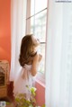 A woman in a white dress looking out a window.