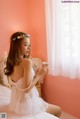 A woman sitting on a bed holding a cup of tea.