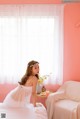 A woman in a white dress sitting on a bed.