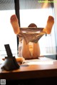 A woman laying on a desk with her feet up in the air.