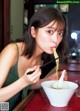 A woman eating noodles with chopsticks in a bowl.