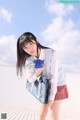 A young woman in a school uniform holding a blue bag.