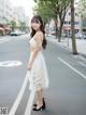 A woman in a white dress standing in the middle of a street.