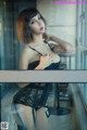 A woman in a black lingerie posing by a window.