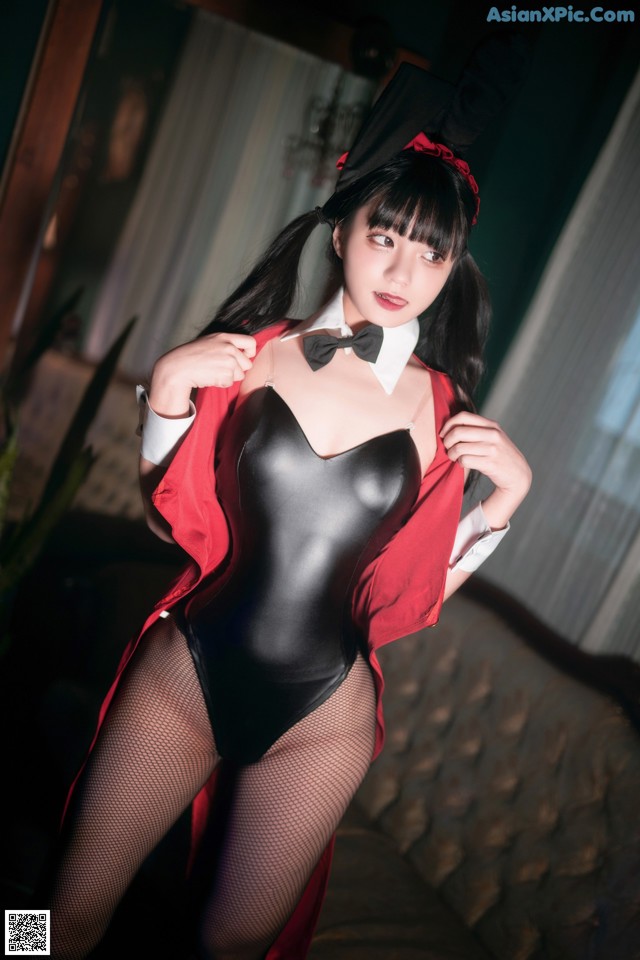 A woman in a black bodysuit and a red jacket posing for a picture.