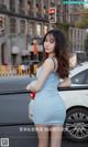 a woman in a blue dress standing next to a car