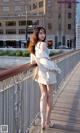 A woman standing on a bridge in a white dress.