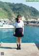 A woman in a school uniform standing by the water.