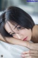 A woman laying on top of a bed next to a window.