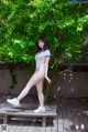 A woman in a white bathing suit posing on a wooden bench.