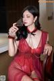 A woman in a red lingerie holding a glass of wine.