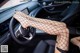 A woman in fishnet stockings is sitting in a car.