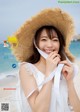 A woman wearing a straw hat on the beach.