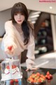 A woman standing in front of a table with a cake and strawberries.