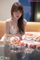 A woman sitting at a table with a cake and strawberries.