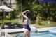 A woman in a bathing suit standing next to a swimming pool.