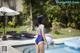 A woman in a blue swimsuit standing next to a swimming pool.