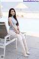 A woman sitting on a white chair next to a pool.