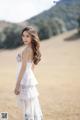 A woman in a white dress standing in a field.