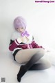 A woman with purple hair sitting on a white surface.