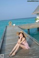 A woman sitting on a wooden dock by the ocean.