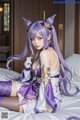 A woman in a purple and white outfit sitting on a bed.