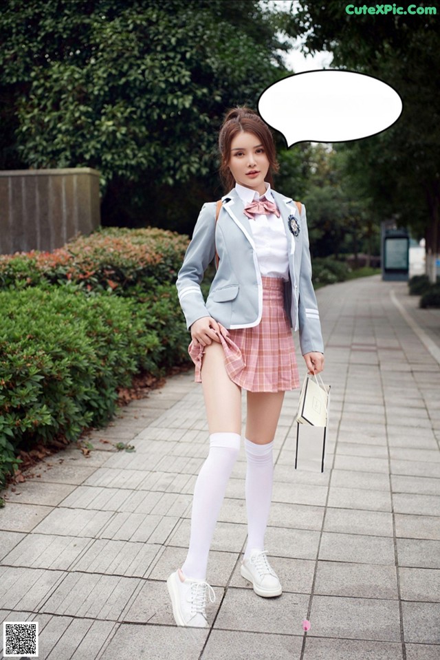 A woman in a school uniform is posing for a picture.
