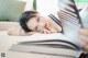 A woman laying on a couch reading a book.