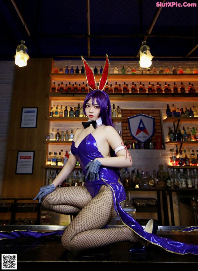 A woman in a bunny costume sitting on a bar.