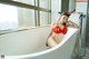 A woman in a red bikini sitting in a bathtub.