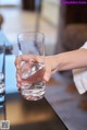 A person holding a glass of water on a table.