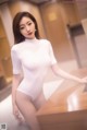 A woman in a white bodysuit posing for a picture.