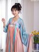 A woman in a blue and pink hanfu dress posing for a picture.