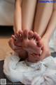 A woman is getting her feet covered in mud.