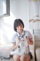 A woman sitting on a couch holding a white cat.