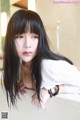 A woman with long black hair leaning on a counter.