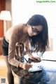 A woman sitting at a table writing on a piece of paper.