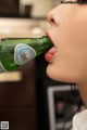 A woman is drinking from a bottle of beer.