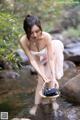 A woman in a pink dress is standing in a stream.