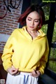 A woman in a yellow hoodie is posing for a picture.