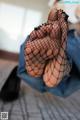 A woman in fishnet stockings is sitting on a bed.