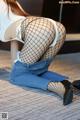 A woman in fishnet stockings and high heels crouching on the floor.