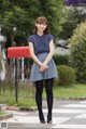 A woman standing in front of a red mailbox.