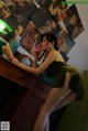 A woman in a green dress sitting at a desk.