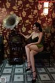 A woman sitting on a chair next to a gramophone.