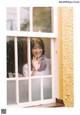 A woman is looking out of a window with her hand up.