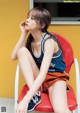 A woman sitting on a red chair with her legs crossed.