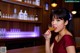 A woman in a red dress drinking a drink at a bar.