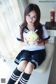 A woman sitting on a window sill holding a stuffed animal.