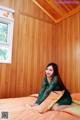 A woman sitting on a bed in a room with wooden walls.